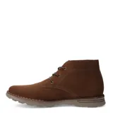 Botas tipo chukka de gamuza color taupe, con cordones y suela de goma gruesa. Presentan costura visible alrededor de la base y el logo de la marca grabado en el lateral.