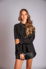 Camisa color crema con cuello alto y mangas largas con volados en los puños. Presenta detalles de crochet y broderie en el frente.