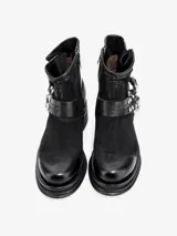 Bota corta de cuero negro, estilo motero, con caña arrugada y suela de plataforma gruesa con envoltura de cuero. Presenta una correa ajustable con hebilla y tachas metálicas alrededor del tobillo.