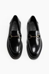 Mocasines negros con trabilla decorativa, forro de satén y suela de 3 cm de grosor.