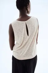 Musculosa color beige claro en punto texturizado con escote redondo y abertura de cerradura con botón en la nuca. Sin mangas.