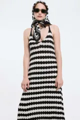 Vestido largo de punto con rayas horizontales blancas y negras, breteles finos y falda acampanada.