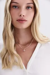 Collar doble, uno dorado y otro plateado, con dije de cristal transparente en forma de corazón.