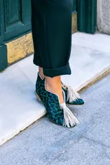 Botines bajos con estampado animal print en tonos verde y negro, con escote en V y borlas decorativas en el empeine.