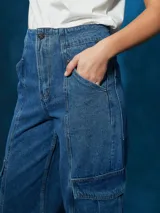 Pantalón de jean de tiro alto, color azul medio, con corte ancho y pierna recta. Presenta costuras marcadas en el centro de las piernas y bolsillos cargo a los lados.
