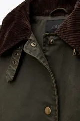 Trench color verde oscuro con cuello solapa combinado en pana marrón y manga larga. Detalle de acabados con trabillas y pinza en espalda. Bolsillos delanteros con solapa y botón a presión. Tejido encerado efecto lavado. Cierre frontal con botones a presión.