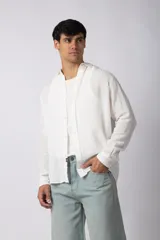 Camisa de lino blanca de manga larga, con cuello clásico y cierre frontal con botones. Corte recto y holgado.