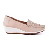 Zapato Korium color beige con capellada lisa, detalle de perforaciones y aplique metálico dorado. Tiene taco corrido blanco y suela marrón.