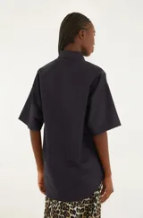 Camisa negra con estampado floral rojo, corte suelto, cuello clásico, cierre frontal con botones y mangas cortas.