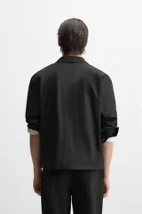 Sobrecamisa negra de algodón con cuello solapa, manga larga con puños abotonados, bolsillos de parche en el pecho y cierre frontal con botones. Corte relaxed fit.