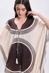 Vestido corto sin mangas color crudo, con escote en V y ajuste en el busto mediante lazos. Presenta un estampado geométrico en tonos marrones y negros.