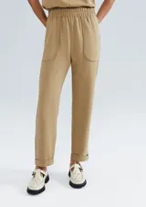 Pantalón carrot color beige, de tiro alto, con cintura elástica y bolsillos laterales.
