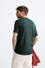 Jersey de punto color marrón oscuro, de corte relajado (relaxed fit), con cuello redondo y manga corta.