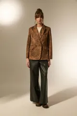 Blazer de poliéster con estampado animal print en tonos marrones y negros, de corte holgado, con cuello solapa y cierre frontal de doble botonadura.