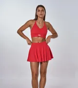 Conjunto deportivo rojo compuesto por un top con tirantes finos cruzados en la espalda y una minifalda tableada.