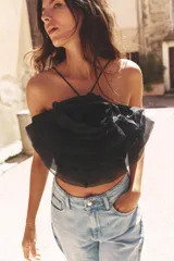 Top negro de organza con cuello halter, tirantes finos y detalle de maxi flor con volumen.