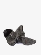 Bota texana corta de cuero color gris oscuro o negro desgastado, con bordados florales en relieve en el empeine y caña. Posee punta afilada y taco bajo.