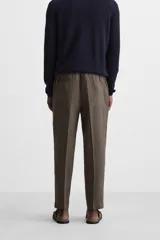 Pantalón de lino color marrón oscuro, de corte recto y relaxed fit. Tiene cintura elástica ajustable con cordón, bolsillos frontales y traseros de parche.