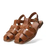 Sandalia tipo franciscana de cuero color marrón, con puntera cerrada tejida en tiras trenzadas y tira de ajuste con hebilla dorada en el tobillo.