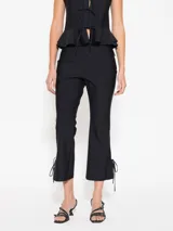 Pantalón negro con cintura rebatida y cierre lateral. Diseño entallado con pinzas delanteras y traseras, corte flare y tajo en el ruedo con moño.