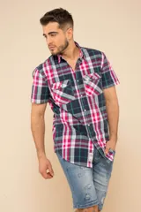 Camisa de manga corta con estampado a cuadros en tonos azul marino, verde, rosa y blanco. Tiene cierre con botones y dos bolsillos con botón en el pecho.