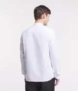 Camisa blanca de corte regular, confeccionada en tela Oxford de algodón, con cuello tipo padre, mangas largas y abotonadura frontal.