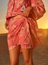 Minifalda pareo color coral con estampado de palmeras en tono beige.
