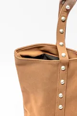 Bolso tipo shopper color negro con apliques de tachas plateadas en los bordes y las asas.