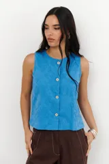 Top color crema con bordado floral, sin mangas, con cuello redondo y cierre frontal con botones.