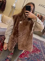 Chaleco de cuero genuino con textura de pelo en color marrón, diseño cruzado con cierre de botón lateral y cuello solapa.