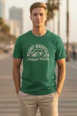 Remera de manga corta color verde oscuro con cuello redondo y un estampado frontal que dice "ROCKY MOUNTAINS COLORADO NATIONAL PARK" con un diseño de montañas en el centro.