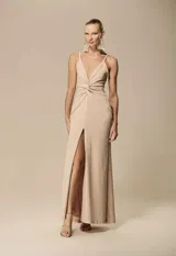Vestido largo color beige con brillo, escote en V profundo, tirantes finos, nudo frontal en la cintura y abertura delantera en la falda.