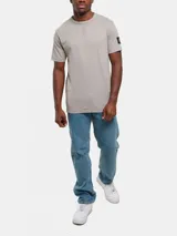 Remera gris de algodón con cuello redondo y manga corta. Presenta una insignia con el monograma de Calvin Klein en la manga izquierda.