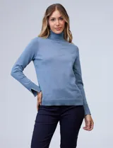 Polera de punto fino marca Nienty, color blanco, con cuello alto volcado y mangas largas con detalle de tajo en los puños.