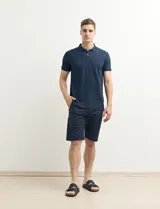 Chomba azul marino con pequeños lunares blancos, cuello clásico con botones y mangas cortas.