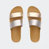 Sandalias Reef Cushion Vista con dos tiras, una plateada y otra dorada, sobre una base color caramelo.