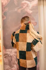 Buzo de cuero lanar con diseño de patchwork en bloques de color, combinando tonos camel, marrón oscuro y beige.