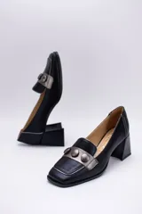 Zapato de cuero negro con aplique plateado y botones forrados en cuero.