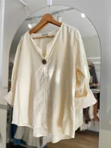 Blusa color crema de pana fina, corte amplio, escote en V y mangas 3/4 con puños anchos.