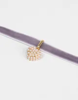Gargantilla tipo choker de terciopelo color lila con dije de corazón dorado cubierto de perlas.