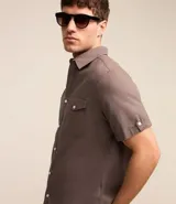 Camisa de hombre de manga corta en lino color blanco, con cuello clásico, botonadura frontal y bolsillo de parche en el pecho. Corte recto.