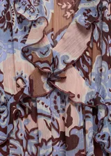 Vestido largo de gasa con estampado paisley en tonos celeste, marrón y rosa. Tiene escote en V con volantes, mangas largas con puños elásticos y lazos, y forro interior.