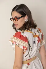 Vestido midi camisero de algodón color natural con estampado de flores, animales y ramas en tonos rojo, marrón, verde y azul. Tiene cuello mao, mangas cortas con volados, bolsillos laterales y cinturón de soga color beige.