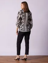 Blusa de gasa estampada marca Figueroa & Flower, color blanco con estampado abstracto en negro. Tiene cuello a la base con escote en V, apertura central con botones y mangas largas ¾ amplias.