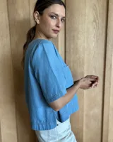 Remera negra con cuello redondo y mangas cortas, con detalle de pespuntes blancos en cuello, mangas, bolsillos frontales y ruedo.