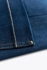 Pantalón de jean de tiro alto color negro con pierna ancha, bolsillos delanteros y traseros, y cierre frontal con cremallera y botón metálico.