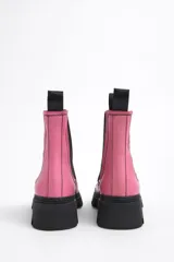 Botines Chelsea de cuero sintético blanco con puntera y suela track de goma negra. Elásticos laterales negros y tirador trasero naranja.