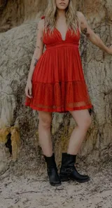 Vestido corto rojo con escote en V profundo y tirantes finos ajustables. El cuerpo es ajustado con frunce en la cintura y la falda corta tiene volados en capas.