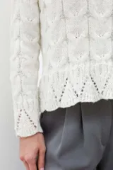 Sweater color crema tejido con diseño de trenzas y calados en el ruedo.