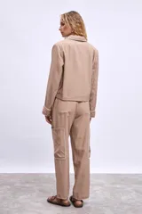 Cazadora color beige con bordados en hilo blanco en cuello, bolsillos y puños.